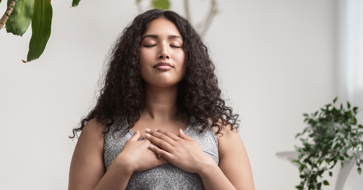 Woman with her eyes closed and hands resting on her chest peacefully