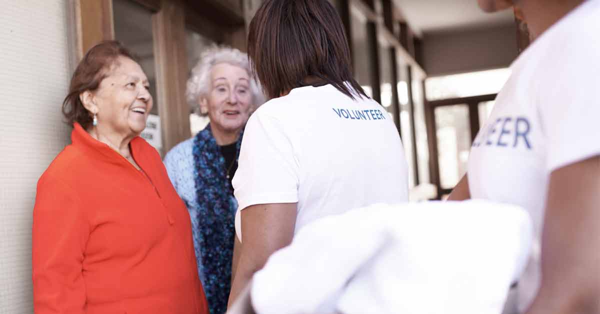Volunteers talking with two elderly women
